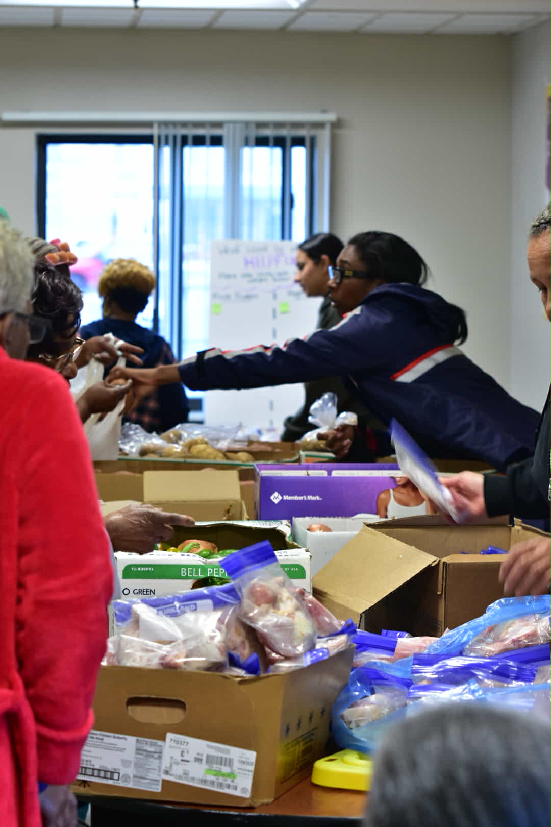 Volunteers hand out bags of fresh produce at a community distribution